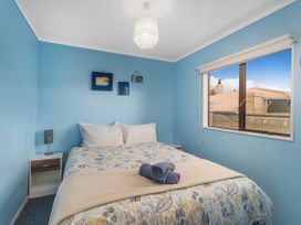 A bedroom with a bed and a side table at Home Away From Home In Whangamata