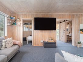 A living room with a television and sofa at Home Away From Home In Whangamata Whangamata