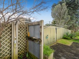 An outdoor shower next to a fence and tree in a garden at Home Away From Home In Whangamata