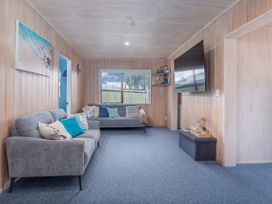 A living room with a sofa and television at Home Away From Home In Whangamata, Whangamata