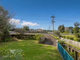 A garden view with grass, fence, trees, and power lines at Home Away From Home In Whangamata, Whangamata