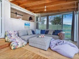 A living room with a sofa and ottoman at Home Away From Home In Whangamata, Whangamata