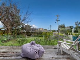 A deck with a bean bag overlooking a garden and power lines at Home Away From Home In Whangamata