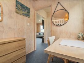 A study area with a table and chair looking into the living room at Home Away From Home In Whangamata