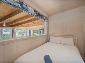 A bedroom with a bed and window at Home Away From Home In Whangamata