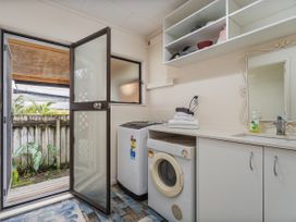 A laundry room with washing machine and dryer at Home Away From Home In Whangamata