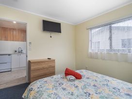 A bedroom with a bed and a television at Home Away From Home In Whangamata in Whangamata