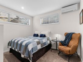 A bedroom with a bed and a chair at Kawau Bay Escape - Snells Beach