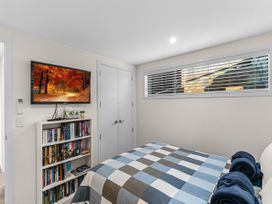 A bedroom with a bed and television at Kawau Bay Escape - Snells Beach