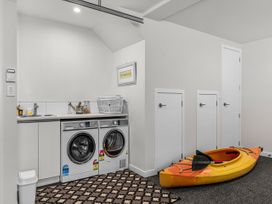A laundry room with a washing machine and kayak at Kawau Bay Escape - Snells Beach