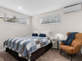 A bedroom with a bed and chair at Kawau Bay Escape - Snells Beach Holiday Home