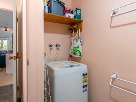 A laundry room with a washing machine and shelf storage at Turangi Holiday Home in Turangi