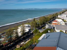 A beach and ocean view with trees and buildings at Cape View - Napier Holiday Home Bluff Hill
