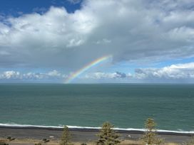 A view of the ocean, rainbow, and trees at Cape View - Napier Holiday Home in Bluff Hill