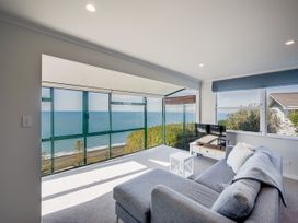 A living room with a sofa and television at Cape View - Napier Holiday Home Bluff Hill