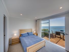 A bedroom with a bed and sliding door to a deck at Cape View - Napier Holiday Home Bluff Hill
