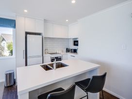 A kitchen with appliances and bar stools at Cape View - Napier Holiday Home in Bluff Hill