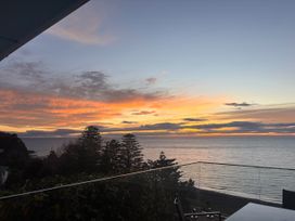 A sunset view over the ocean with trees at Cape View - Napier Holiday Home in Bluff Hill