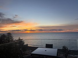 A balcony with a table and chairs overlooking the ocean at Cape View - Napier Holiday Home in Bluff Hill