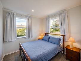 A bedroom with a bed and windows at Cape View - Napier Holiday Home Bluff Hill