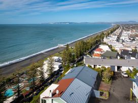 A coastal view with houses and trees near the shoreline at Cape View - Napier Holiday Home Bluff Hill