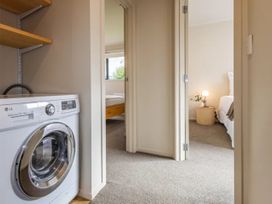 A laundry room with a washing machine and access to a bedroom at Alpine Retreat - Ohakune Holiday Home in Ohakune