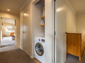 A laundry room with a washing machine and storage at Alpine Retreat - Ohakune Holiday Home