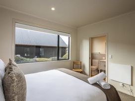 A bedroom with a bed and chair at Alpine Retreat - Ohakune Holiday Home in Ohakune