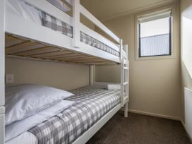 A bunk bed with gray checkered bedding at Alpine Retreat - Ohakune Holiday Home in Ohakune
