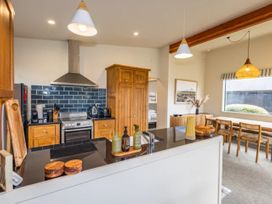 A kitchen with cabinets and a dining table at Alpine Retreat - Ohakune Holiday Home, Ohakune
