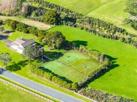 A tennis court and a house in a field at Mangawhai Heads Holiday Home in Mangawhai