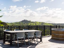 A table with chairs and a hot tub on an outdoor patio at Mangawhai Heads Holiday Home in Mangawhai