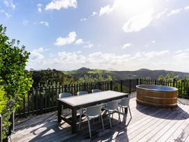 An outdoor area with a dining table and hot tub at Mangawhai Heads Holiday Home, Mangawhai
