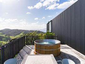 An outdoor area with a hot tub on a deck at Mangawhai Heads Holiday Home in Mangawhai