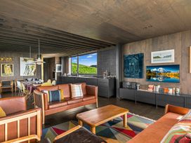 A living room with a sofa, chairs, and a dining table at Mangawhai Heads Holiday Home, Mangawhai
