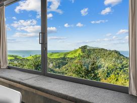 A view through a window showing mountains and ocean at Mangawhai Heads Holiday Home Mangawhai