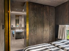 A bedroom with a bed and attached bathroom at Mangawhai Heads Holiday Home in Mangawhai