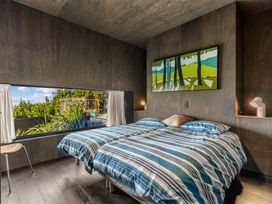 A bedroom with a bed and artwork on the wall at Mangawhai Heads Holiday Home Mangawhai