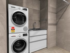 A laundry room with a washing machine and a dryer at Mangawhai Heads Holiday Home, Mangawhai