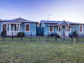 Two blue houses with a fence in front at Taylor Lodge Adventure Base -  Erua Holiday Home