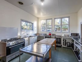 A kitchen with stove, sink, and work table at Taylor Lodge Adventure Base - Erua Holiday Home National Park