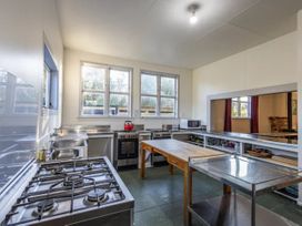 A kitchen with a stove, sink, and tables at Taylor Lodge Adventure Base - Erua Holiday Home in National Park
