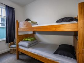 A bedroom with a bunk bed and chair at Taylor Lodge Adventure Base -  Erua Holiday Home National Park