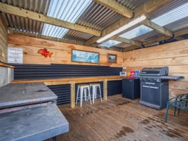 An outdoor kitchen with grill, refrigerator, and table at Taylor Lodge Adventure Base -  Erua Holiday Home National Park