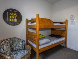 A bedroom with a bunk bed and a floral couch at Taylor Lodge Adventure Base - Erua Holiday Home National Park