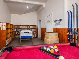A pool table with balls in front of a bookcase and freezer at Taylor Lodge Adventure Base - Erua Holiday Home National Park
