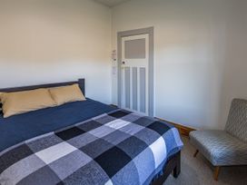 A bedroom with a bed and chair at Taylor Lodge Adventure Base - Erua Holiday Home in National Park