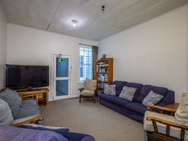 A living room with a television and bookshelf at Taylor Lodge Adventure Base - Erua Holiday Home National Park