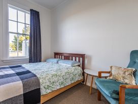 A bedroom with a bed and chair at Taylor Lodge Adventure Base - Erua Holiday Home National Park