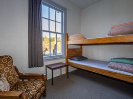 A bedroom with a bunk bed and a chair at Taylor Lodge Adventure Base -  Erua Holiday Home National Park